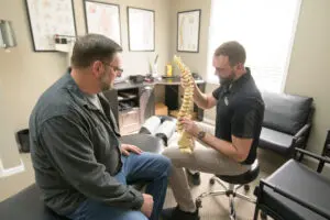 Chiropractor explaining spine model to patient.